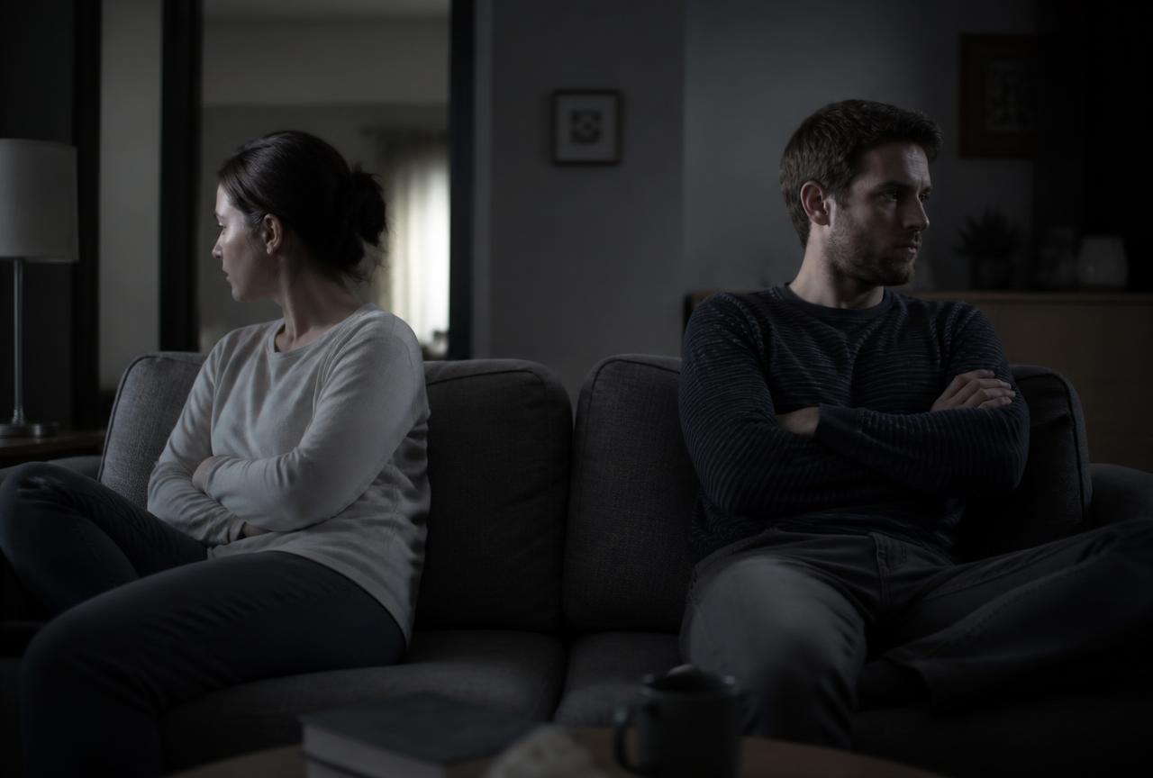 Casal sentado distante no sofá, em silêncio